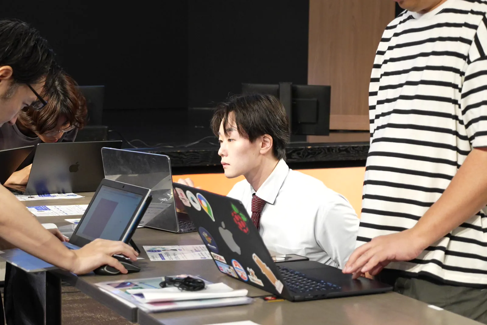 長机のノートPCに向かって作業する参加者と横に立つ人